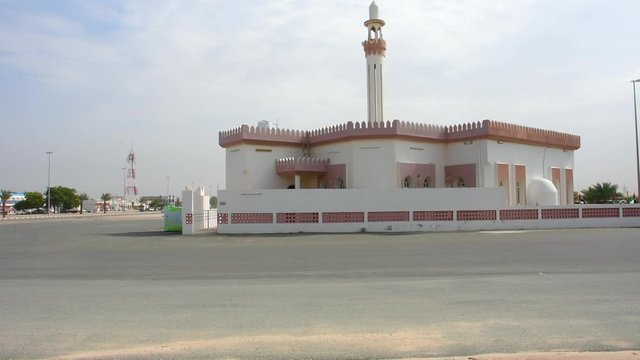 White Mosque in a residential area in the Middle East on a cloudy afternoon in the late afternoon sunshine during call to prayer.