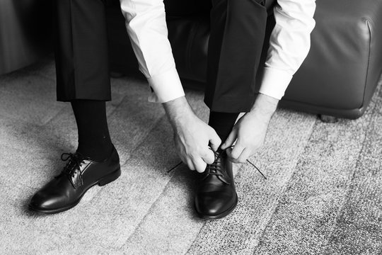 Businessman or groom tying shoe laces preparing