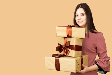 Girl with three gifts in her hands. A young teenager girl carries gifts in her hands. Delicate soft beige background.