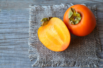 Fresh ripe organic Persimmon or Kaki fruit whole and half on old wooden table.Diospyros kaki.Healthy food vegetarian or raw diet concept.Selective focus.