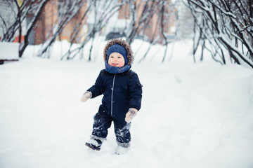 Fototapeta na wymiar Little boy in a snowy winter forest among trees in hoarfrost