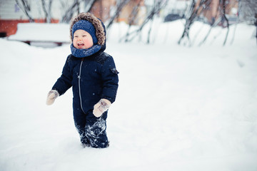 Little boy in a snowy winter forest among trees in hoarfrost