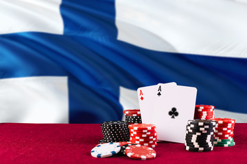 Finland casino theme. Aces in poker game, cards and chips on red table with national flag...