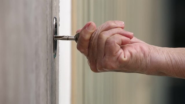 Senior Woman's hand use a key for lock or unlock wooden door, Close up & Macro shot, Selective focus, Security concept