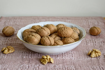 Walnuts in white plate on table covered with beige napkin, close-up.