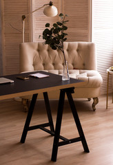 Loft style. Stylish scandinavian interior of living room with small design table and sofa. Beige walls, plants.
