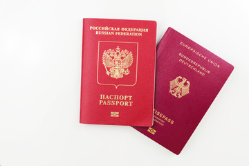 German passport behind Russian passport isolated on white background