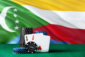 Comoros casino theme. Two ace in poker game, cards and black chips on green table with national...