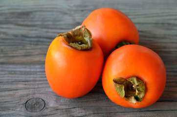 Fresh ripe organic Persimmon or Kaki fruit on old wooden table. Diospyros kaki.Healthy food vegetarian or raw diet concept.Copy space.Selective focus.