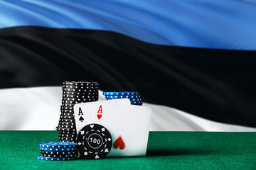 Estonia casino theme. Two ace in poker game, cards and black chips on green table with national flag background. Gambling and betting.