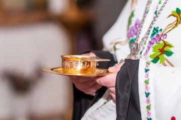 Priest holding gold cup with wine in the hands