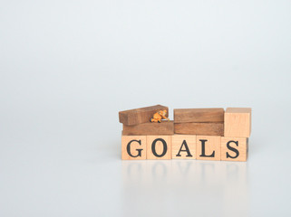 Miniatures as workers are working for wooden block printed GOALS. The concept is intention to accomplish.