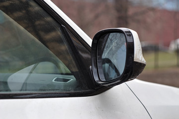 side mirror of the next car in the parking lot