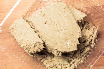 Large piece of fresh halva in transparent package on wooden board.