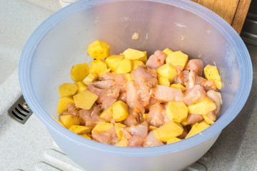 Sliced chicken fillets with potatoes in deep blue bowl.