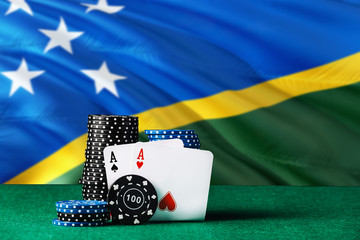 Solomon Islands casino theme. Two ace in poker game, cards and black chips on green table with...