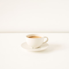 Cup of coffee with milk on white table. Minimal morning breakfast concept.