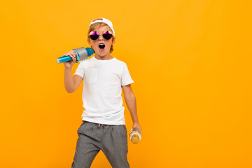 young boy with two microphones sings on a yellow bright background