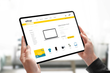 Online shopping website concept on tablet in woman hands. Woman search for laptop computer online.