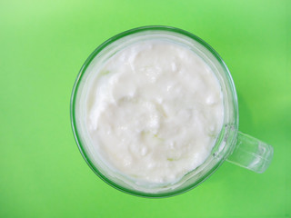 Homemade yogurt in a cup on green background,  top view 