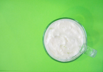 Homemade yogurt with kiwi in a transparent cup on green background. Healthy breakfast and food, detox concept. Copy space, place for text, top view