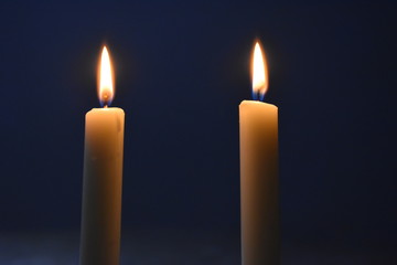 Two candles burning in the dark