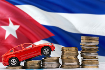 Cuba savings concept. Money for new automobile, toy car and coin piles standing on national flag background. Copy space for text.