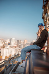 Young guy in blue hat looking at camere on roof