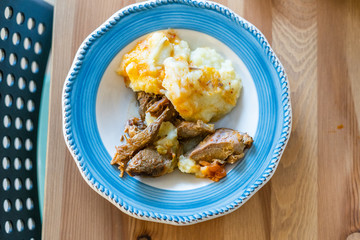 Homemade Turkey Meat with Potato Puree in Plate on Wooden Table at Kitchen.