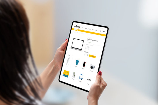 Modern online shop on tablet display in woman hands. Flat design e-commerce web site with technology products. Concept of shopping online - Powered by Adobe