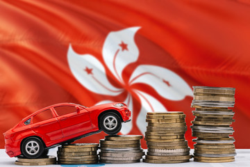 Hong Kong savings concept. Money for new automobile, toy car and coin piles standing on national flag background. Copy space for text.