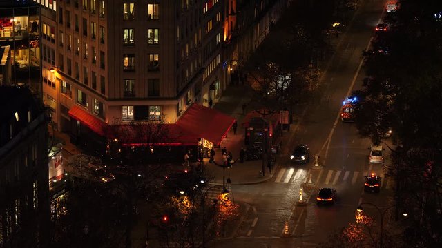 Paris, France in evening: aerial view of street with cafe and ambulance passing.