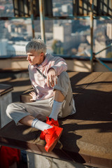 Obraz premium Young guy in red sneakers looking away on roof