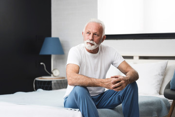 Fototapeta premium Senior man sitting on bed in morning