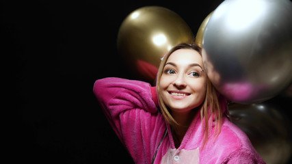 girl in pink kigurumi pajamas with balloons. pajama party