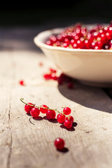 Detail on a bunch of red currant in a bowl on a wooden table