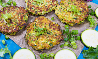 Zucchini pancakes with chives on a wooden table. - 309769847
