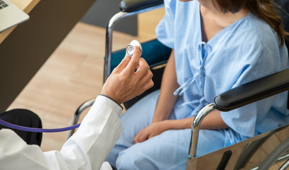 Fototapeta premium Close-up of doctor using stethoscope to exam woman patient heart