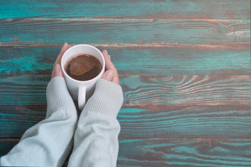 Woman's hands in a sweater with a cup of coffee on a sunny morning with copy space