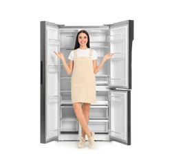 Young woman near empty refrigerator on white background