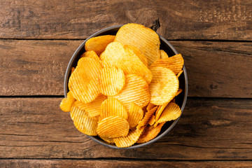 Potato chips in bowl on rustic wooden table. Top view. Close up
