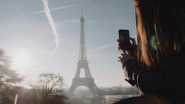 Happy excited local blogger woman taking a video of epic sunset Paris Eiffel Tower sky panorama with phone slow motion.