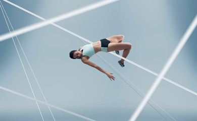 Female athlete running and jumping. Side view shot of healthy woman working out against hi tech...