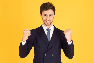 A man in a suit with a tie Handsome looking face with beard In Madluk, businessmen are delighted by raising their hands and raising their fists on both sides. In the yellow background