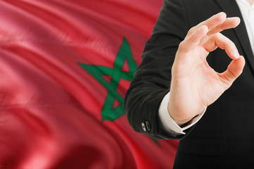 Fototapeta premium Morocco acceptance concept. Elegant businessman is showing ok sign with hand on national flag background.