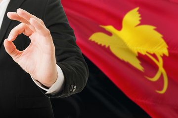 Fototapeta premium Papua New Guinea acceptance concept. Elegant businessman is showing ok sign with hand on national flag background.