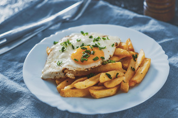 fried egg with potato in a white plate on table