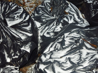 black plastic bags stuffed with garbage and sprinkled with snow