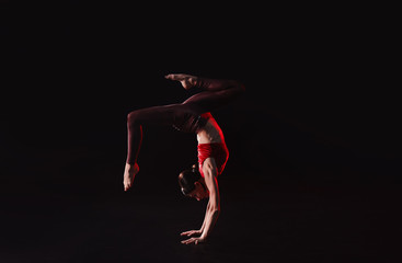 Fototapeta premium Young woman performing acrobatic element on stage indoors