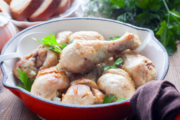 Fried chicken drumsticks in a pan on a wooden table, selective focus